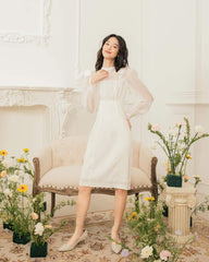 Organza knee-length dress with sheer puff sleeves and bow accents for feminine elegance