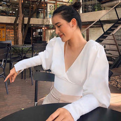 Silk blouse with puff sleeves, V-neckline, and lace-up back detail for elegant styling