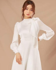 Silk long-sleeve high-neck gown with bow tie detail and flowing A-line floor-length skirt