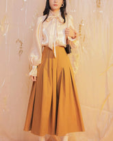 Silk blouse with bow tie neck and ruched cuffs featuring soft sheen and romantic silhouette