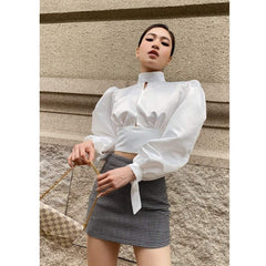 Silk blouse with puff sleeves, high neckline, open back, and waist tie detailing