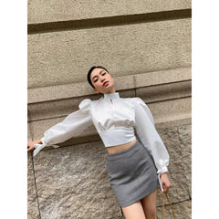 Silk blouse with puff sleeves, high neckline, open back, and waist tie detailing