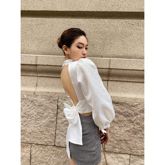 Silk blouse with puff sleeves, high neckline, open back, and waist tie detailing