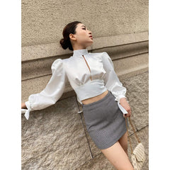 Silk blouse with puff sleeves, high neckline, open back, and waist tie detailing