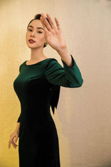Velvet midi dress with long sleeves, boat neckline, and low back bow detail