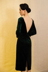 Velvet midi dress with long sleeves, boat neckline, and low back bow detail